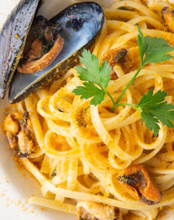 Spaghetti con cozze, bottarga e prezzemolo, un tripudio di sapori marini e freschezza.