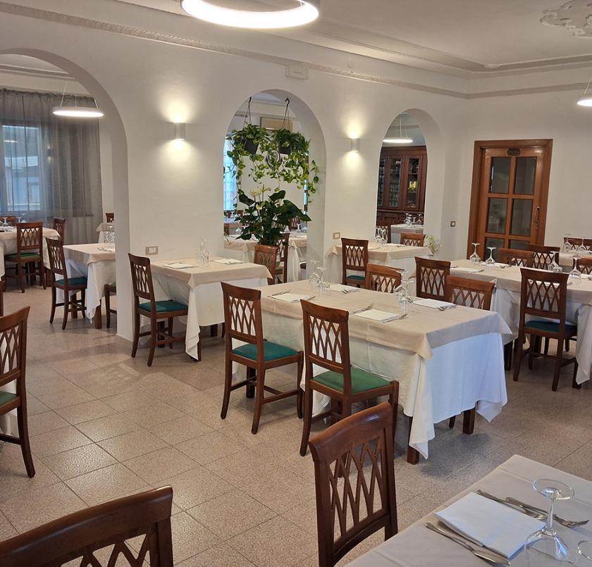 Ristorante elegante con tavoli apparecchiati, archi, lampadari scintillanti e atmosfera accogliente.