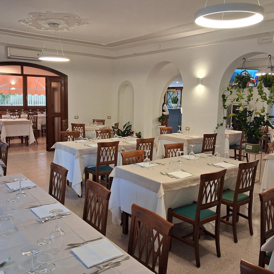Elegante sala da pranzo con lampadari scintillanti, tavoli apparecchiati e atmosfera accogliente.